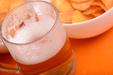 Image showing Glass of light beer and potato chips on a wooden table