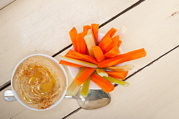 Image showing fresh hummus dip with raw carrot and celery 