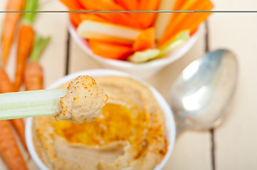 Image showing fresh hummus dip with raw carrot and celery 