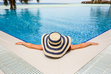 Image showing Woman in straw hat relaxing swimming pool