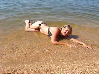 Image showing girl laying on sand at the seacoast