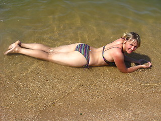 Image showing The girl laying on sand at the seacoast