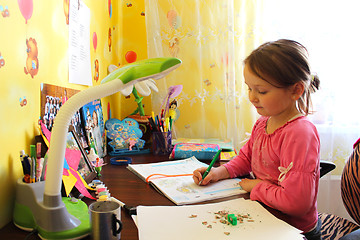 Image showing girl the schoolgirl learns lessons at the table