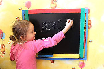 Image showing girl writes on blackboard word the peace