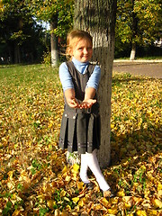 Image showing little girl with yellow leaf in autumn