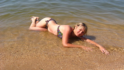 Image showing girl laying on sand at the seacoast
