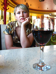 Image showing glass of red wine on the table and a lonely girl