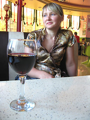 Image showing glass of red wine on the table and a girl