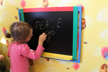 Image showing girl writes on a blackboard a word the peace