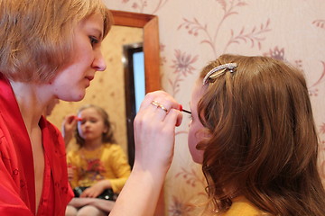 Image showing mother makes up daughter's face before a mirror