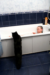 Image showing little girl taking a bath with curious black cat