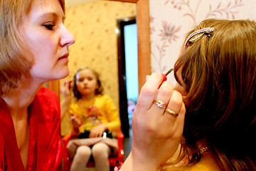 Image showing mother makes up daughter's face before a mirror