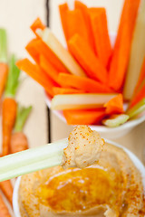 Image showing fresh hummus dip with raw carrot and celery 