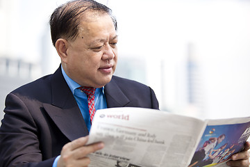 Image showing Asian businessman reading newspaper