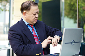 Image showing Asian businessman looking at watch