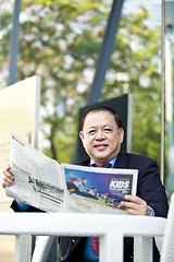 Image showing Asian businessman reading newspaper