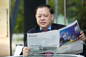 Image showing Asian businessman reading newspaper