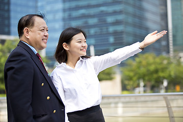 Image showing Asian businessman and young female executive pointing at a direction