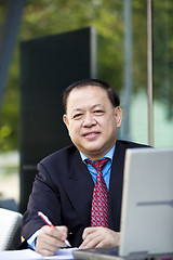 Image showing Asian businessman writing proposal