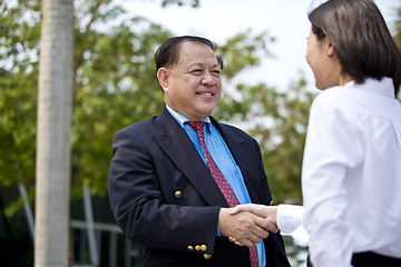 Image showing Asian businessman and young female executive shaking hands