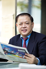 Image showing Asian businessman reading newspaper