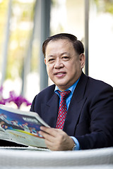 Image showing Asian businessman reading newspaper