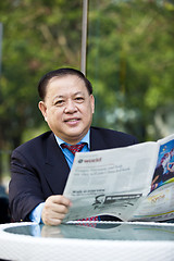 Image showing Asian businessman reading newspaper