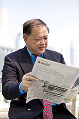 Image showing Asian businessman reading newspaper