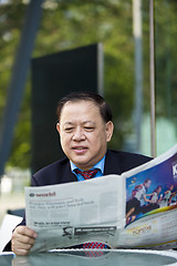 Image showing Asian businessman reading newspaper