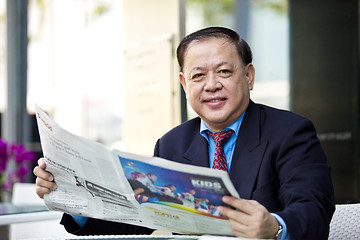 Image showing Asian businessman reading newspaper