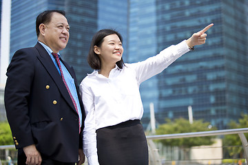 Image showing Asian businessman and young female executive pointing at a direction