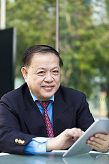 Image showing Asian businessman using tablet