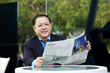 Image showing Asian businessman reading newspaper