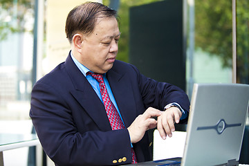 Image showing Asian businessman looking at watch
