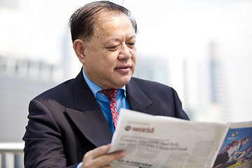 Image showing Asian businessman reading newspaper