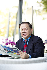 Image showing Asian businessman reading newspaper