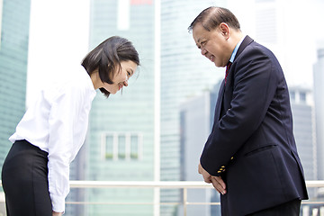 Image showing Asian businessman & young female executive bowing