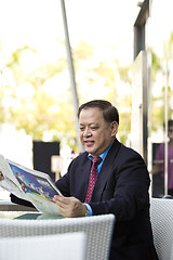 Image showing Asian businessman reading newspaper