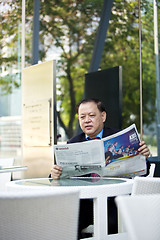 Image showing Asian businessman reading newspaper