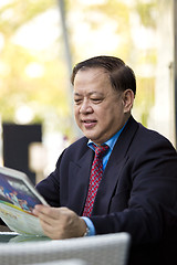 Image showing Asian businessman reading newspaper