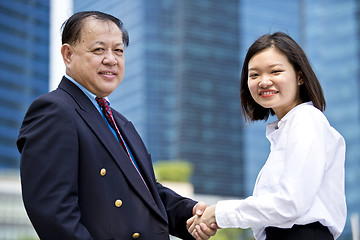 Image showing Asian businessman & young female executive shaking hands