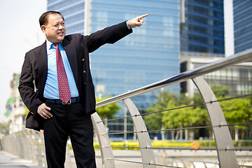 Image showing Asian businessman smiling pointing at a direction