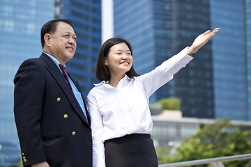 Image showing Asian businessman & young female executive pointing at a direction
