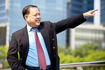 Image showing Asian businessman smiling pointing at a direction