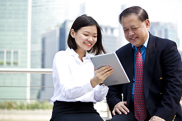 Image showing Asian businessman & young female executive looking at tablet