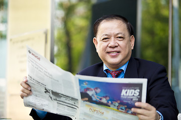 Image showing Asian businessman reading newspaper