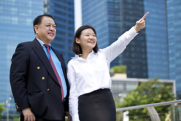 Image showing Asian businessman & young female executive pointing at a direction