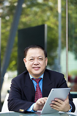 Image showing Asian businessman using tablet