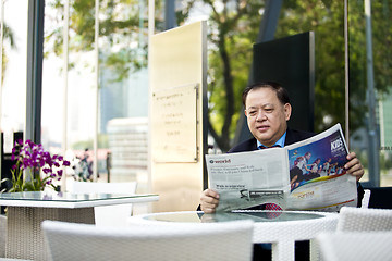 Image showing Asian businessman reading newspaper