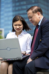 Image showing Asian businessman and young female executive using laptop